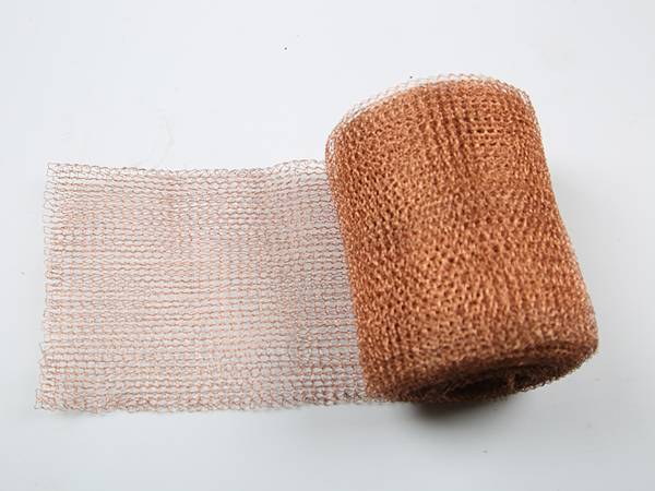 A roll of knitted copper wire mesh on gray background.