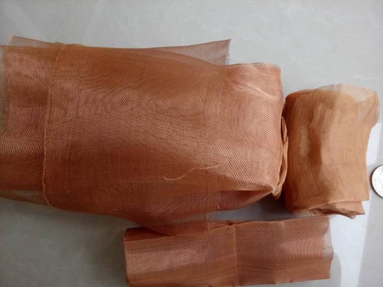 Three small rolls of copper mesh are placed on the ground.