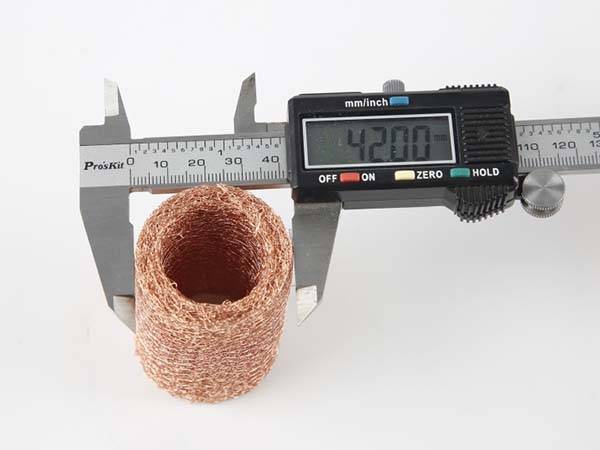 A caliper is measuring the tube form compressed copper knitted mesh outer diameter.