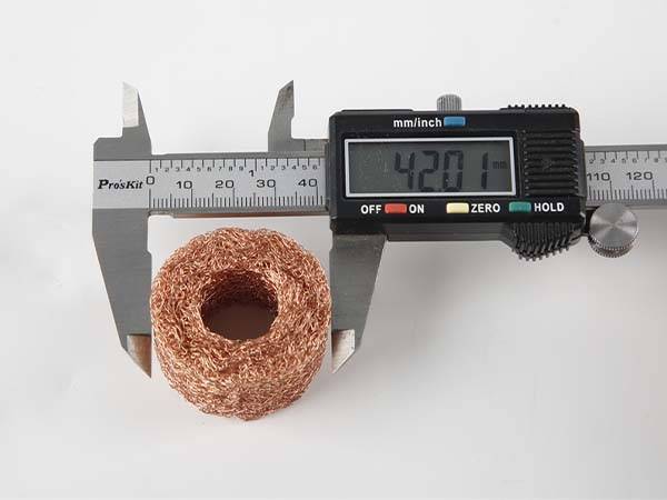 A caliper is measuring the ring form  compressed copper knitted mesh outer diameter.