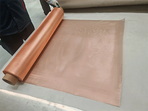 The worker unfolds a roll of micro expanded copper mesh.