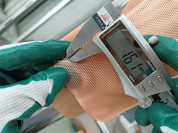 The worker measures the SWD of micro expanded copper mesh with a caliper.